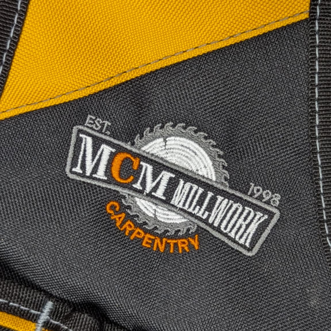 Close-up of a gray work vest with yellow accents and a visible brand logo.